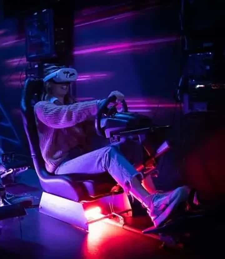 Four people racing on real racing seats with VR headsets on