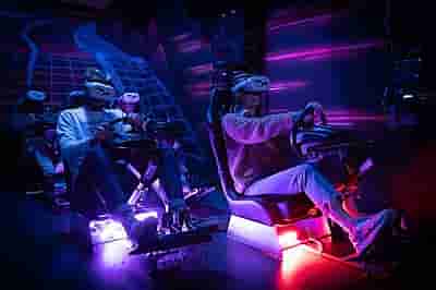 Four people racing on real racing seats with VR headsets on