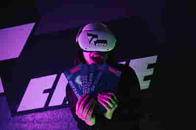 Woman in Meta Quest 2 headset holding 5 VRcafe Haarlem giftcards