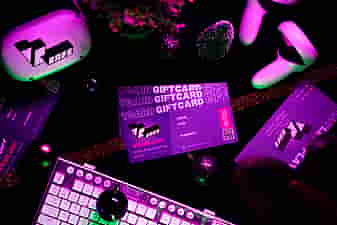 3 VRcafe Haarlem giftcards laying on a black table near a white/silver keyboard and Christmas decorations