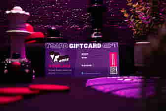 VRcafe Haarlem giftcard standing against a purple wall with chess figures and plants around it