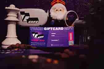 VRcafe Haarlem giftcard standing against a purple wall with Sinterklaas plushie and controllers nearby