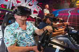 4 men racing on a F1 track in Valve Index headsets during a company outing