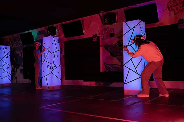 Two people shooting each other in a laser tag game hiding behind towers in real life