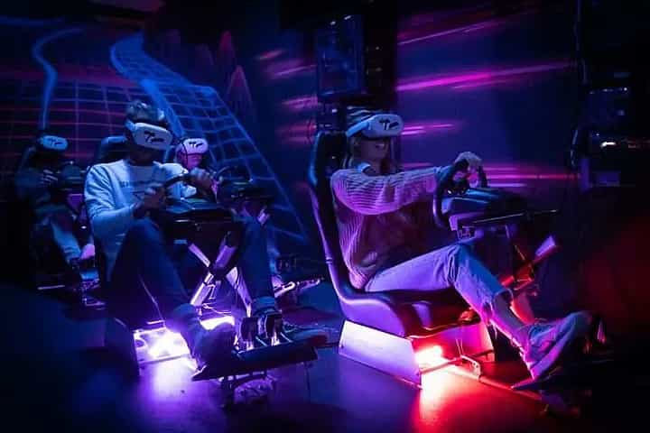 Four people racing on real racing seats with VR headsets on