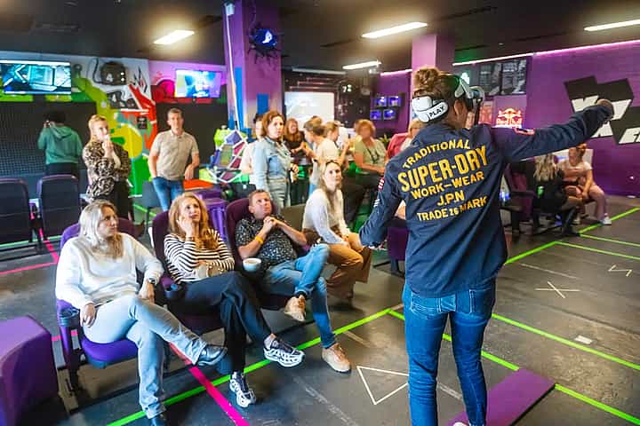 Woman in a black T-shirt standing on a plank while wearing a Meta Quest 2 headset during a company outing at VRcafe Haarlem