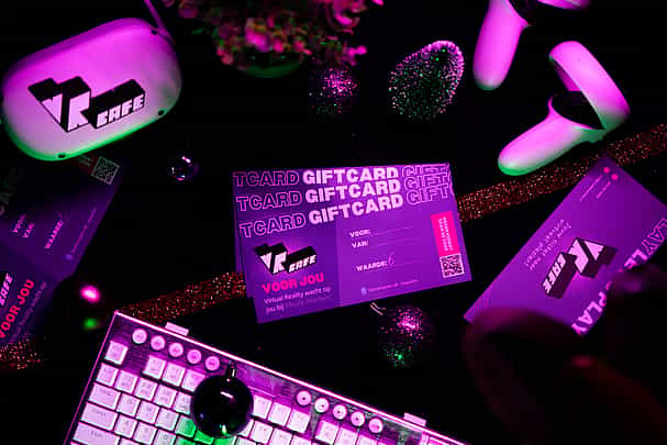 3 VRcafe Haarlem giftcards laying on a black table near a white/silver keyboard and Christmas decorations