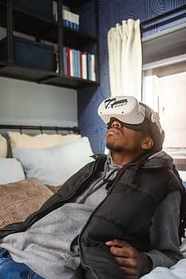 A man laying down on his bed at home watching a Virtual Reality video using a Meta Quest 2 headset rent from VRcafe Haarlem