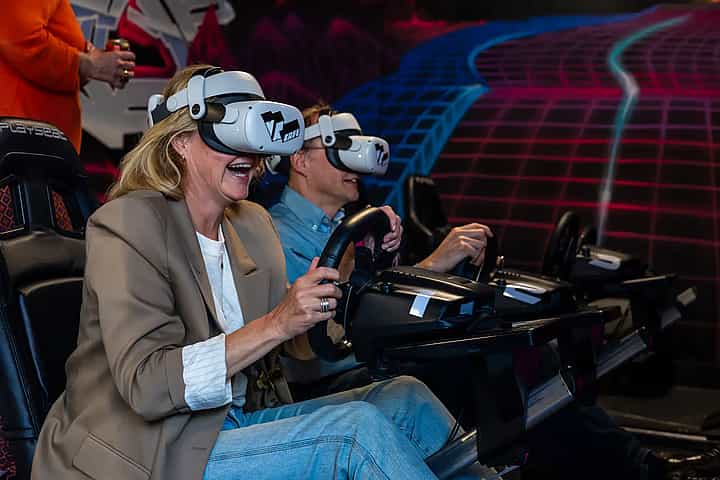 Two people racing on a Formula 1 simulator in Meta Quest 2 headsets during a company outing