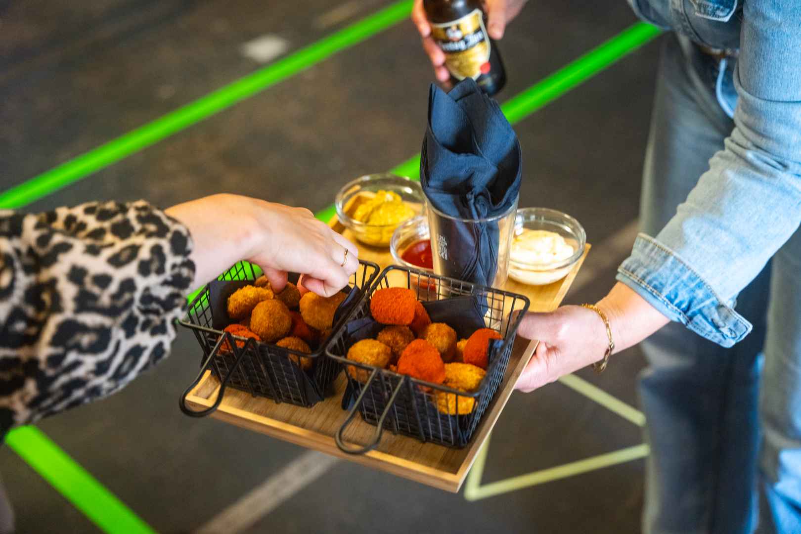 A wooden tray with bitterballen, tissues and different sauces served during a big teambuilding outing