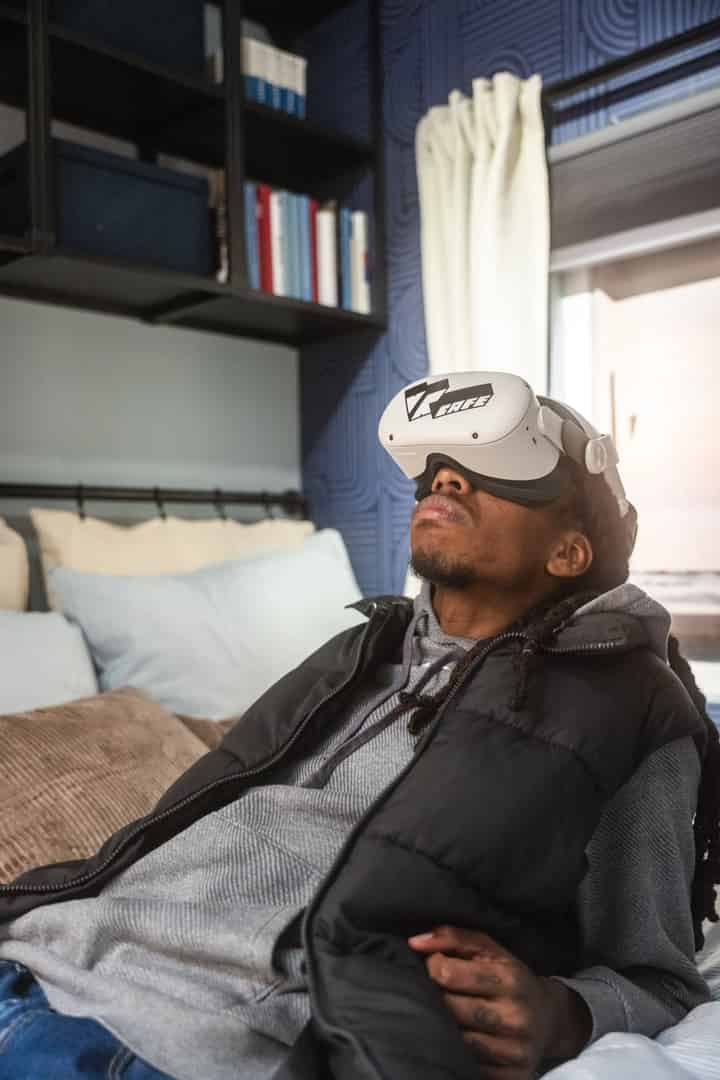 A man laying down on his bed at home watching a Virtual Reality video using a Meta Quest 2 headset rent from VRcafe Haarlem