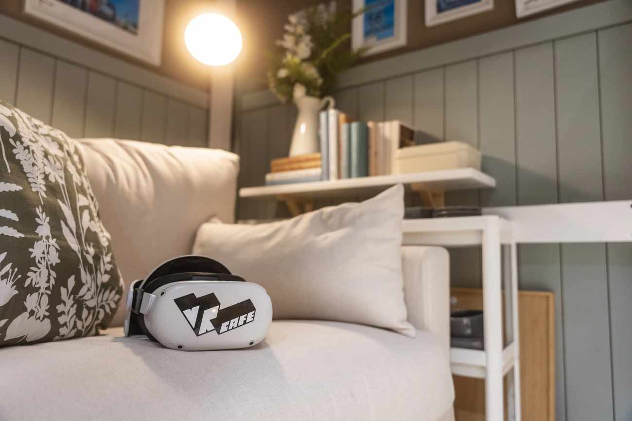 Meta Quest 2 headset rent from VRcafe Haarlem laying on a white sofa with a warm light lamp shining on it
