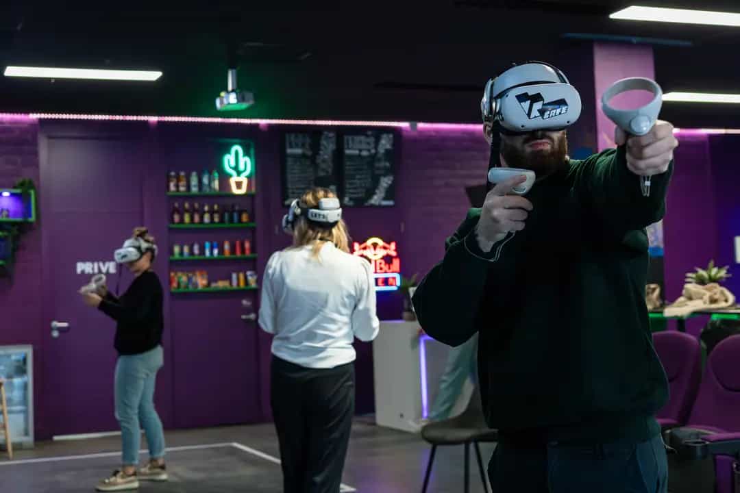 A group of three people playing a VR game together during a friends outing at VRcafe Haarlem with a purple wall behind them