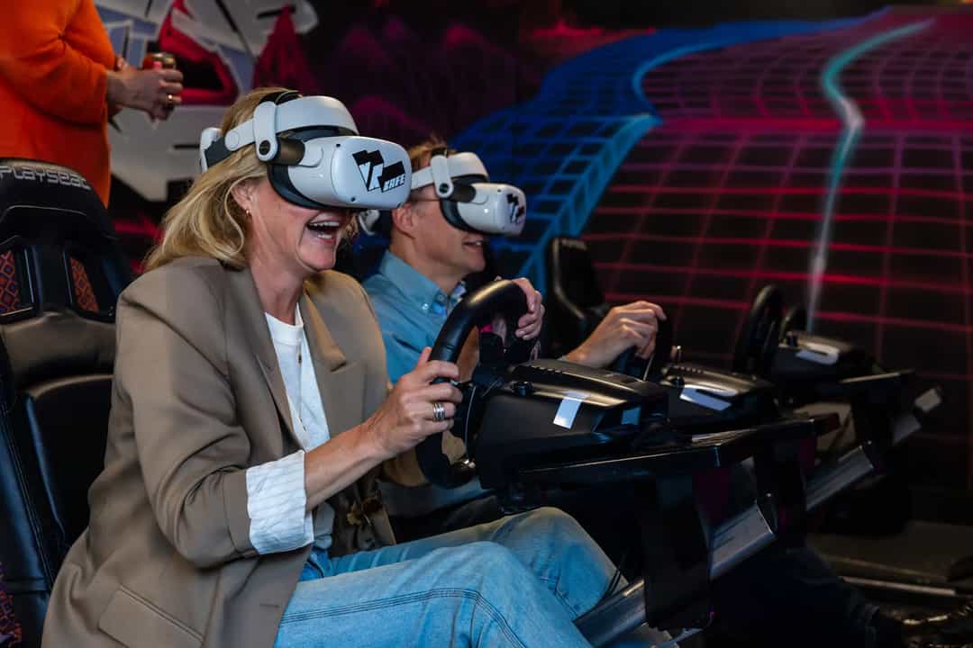 Two people racing on a Formula 1 simulator in Meta Quest 2 headsets during a company outing