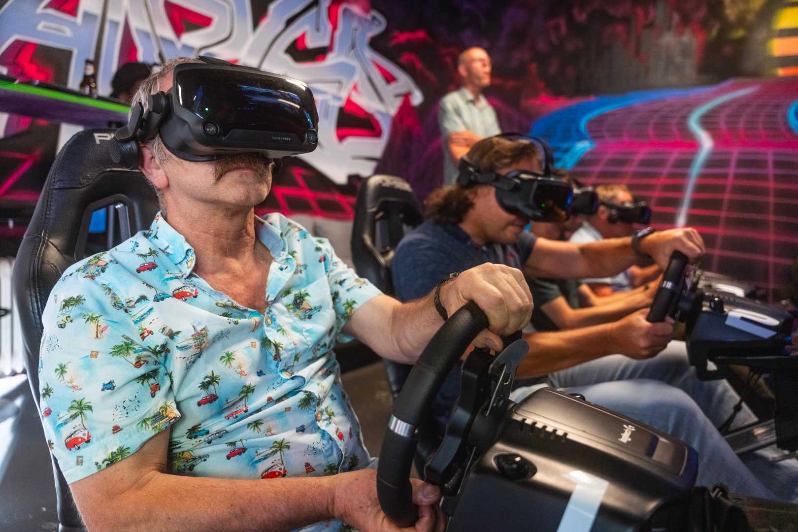 4 men racing on a F1 track in Valve Index headsets during a company outing